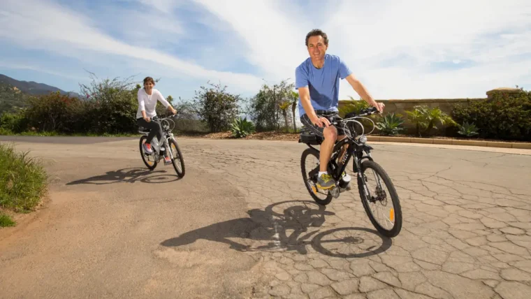 Two people riding electric bikes on a road