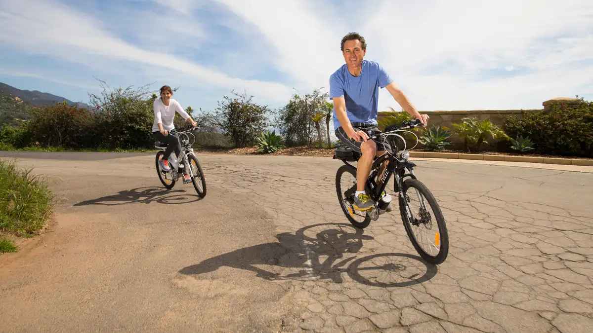 Two people riding electric bikes on a road