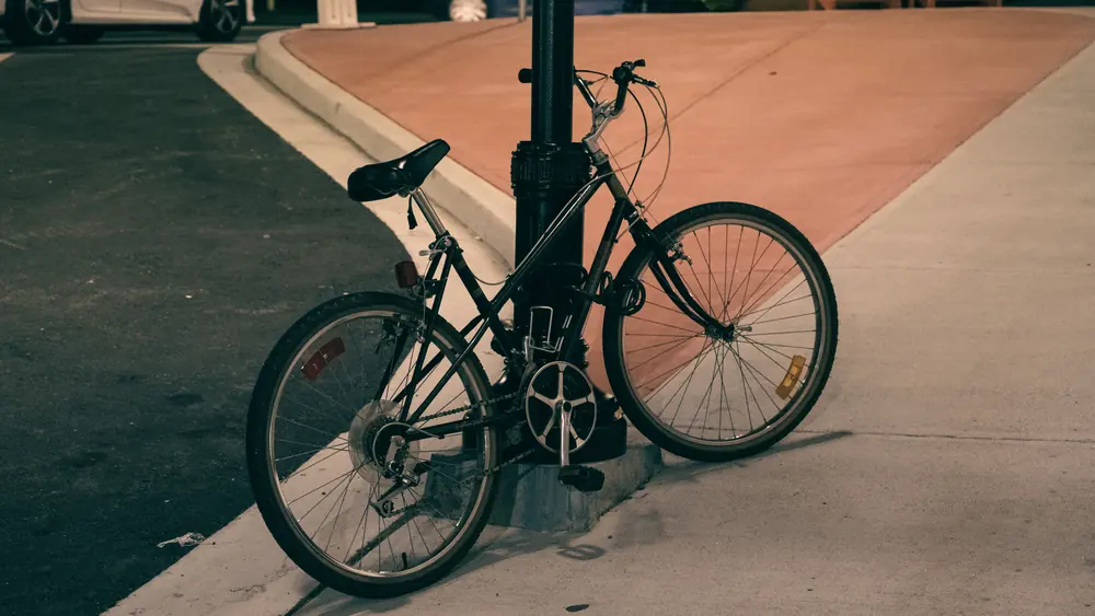 A bicycle locked to a street post in the city