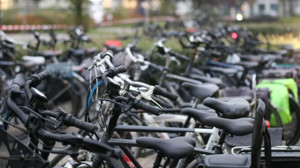 Close-up of a front bike light mounted on handlebars in an urban setting