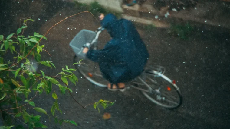 Cyclist commuting in heavy rain on a wet urban street