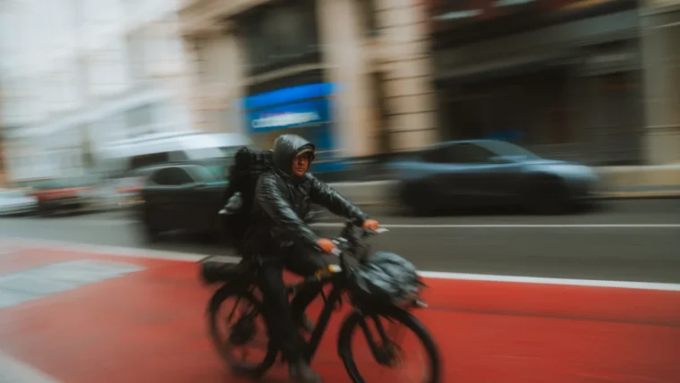 Cyclist wearing a waterproof jacket riding through rain on a city street