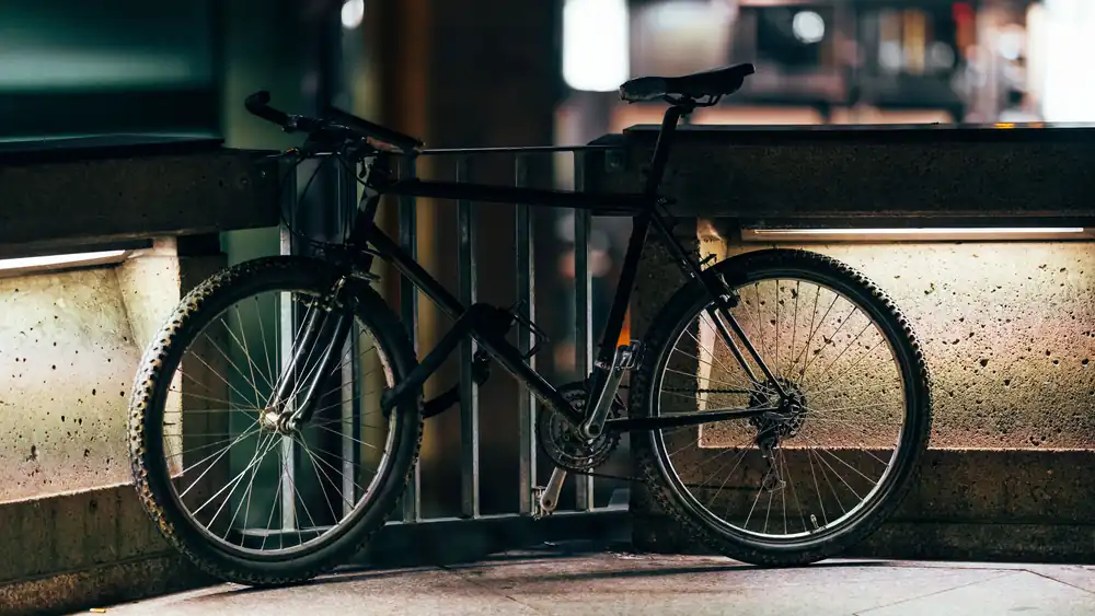 A black bike leaning against a metal railing on a city street at night