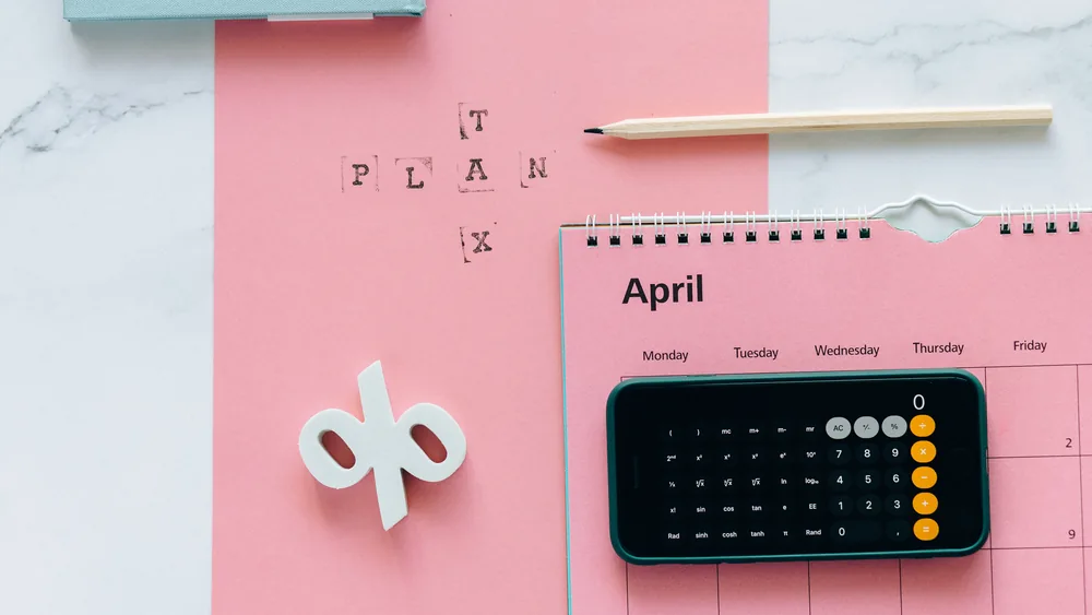 April calendar, calculator, pencil and percent sign laid out for planning payments