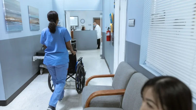 A nurse pushing a wheelchair along a hospital corridor