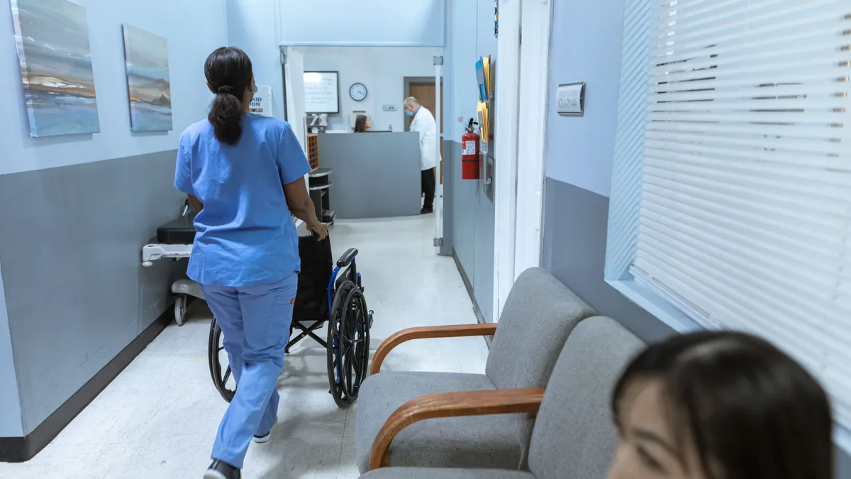 A nurse pushing a wheelchair along a hospital corridor