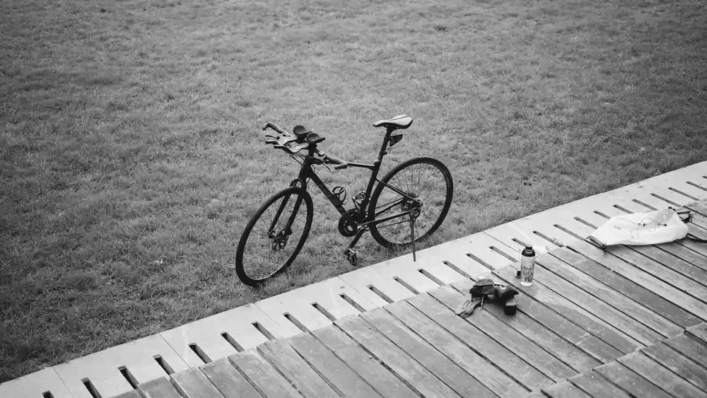 A flat-bar hybrid bike resting on its kickstand beside a wooden walkway