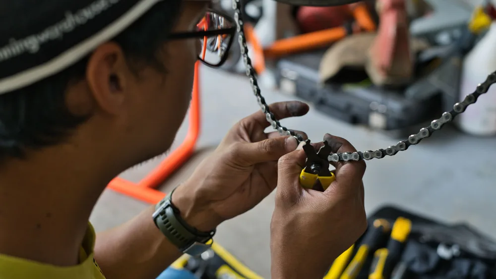 A bike mechanic fitting a chain with a pair of chain pliers